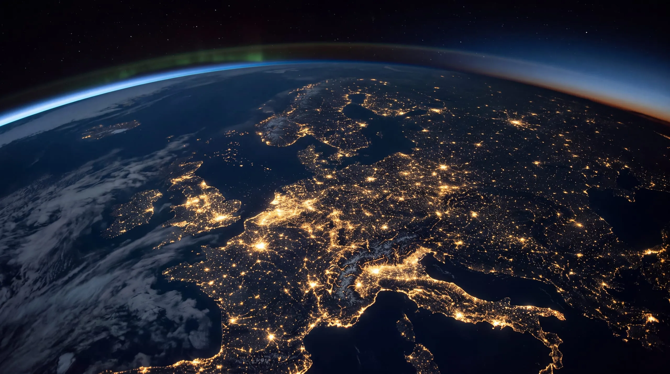Europe seen from orbit at night, city lights on and dawn coming in from the east, the curve of the Earth at the top.